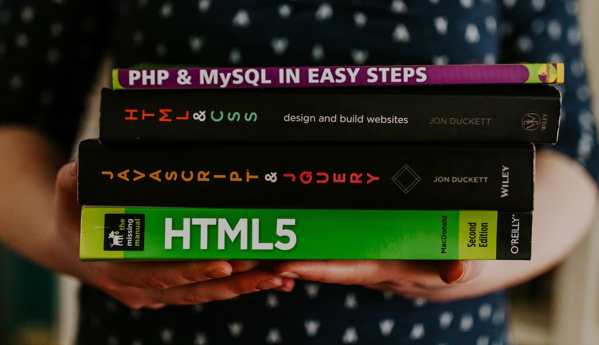 woman holding 4 books on coding