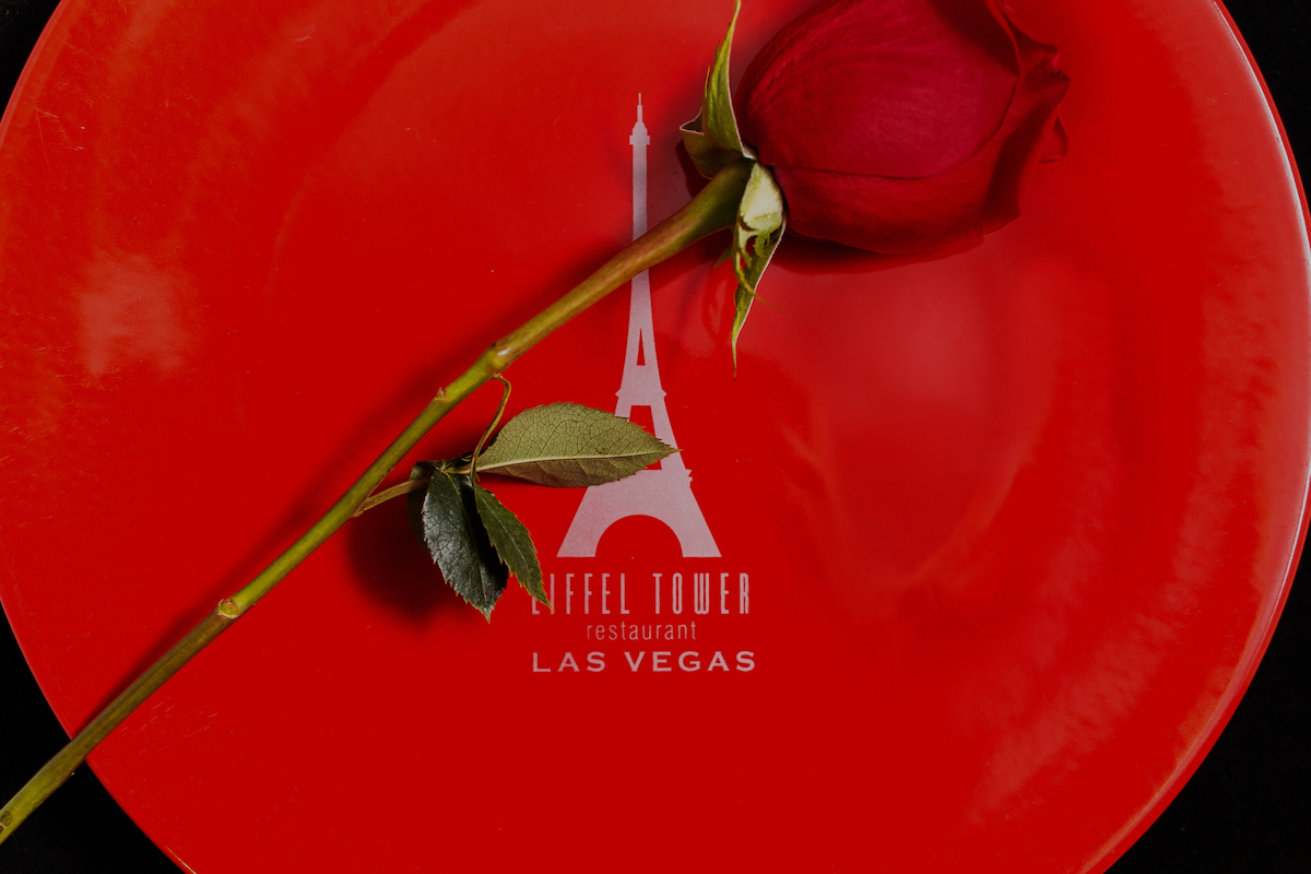 Eiffel Tower logo printed on a red plate. A red rose over the plate.